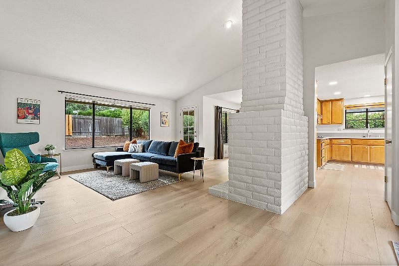 View from the entry - living room with cozy fireplace and backyard access, dining room, and kitchen to the right.