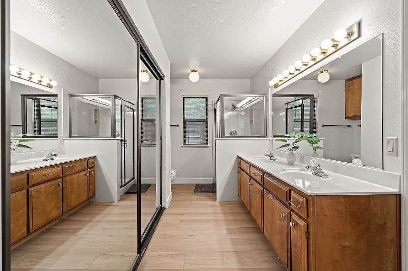 Primary bath with double closets, dual sinks, and glass shower enclosure.