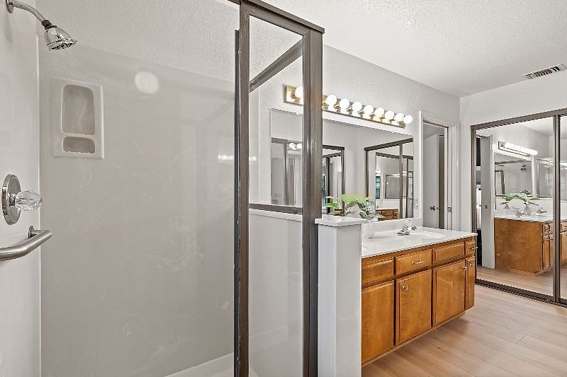 Primary bath glass shower enclosure and view of secondary closet.