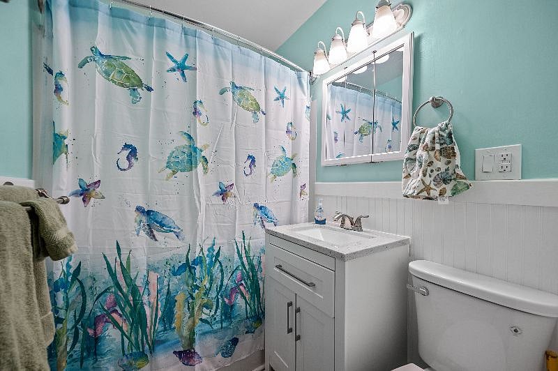 Bathroom with tub and shower combo. Furnished with towels and toiletries.