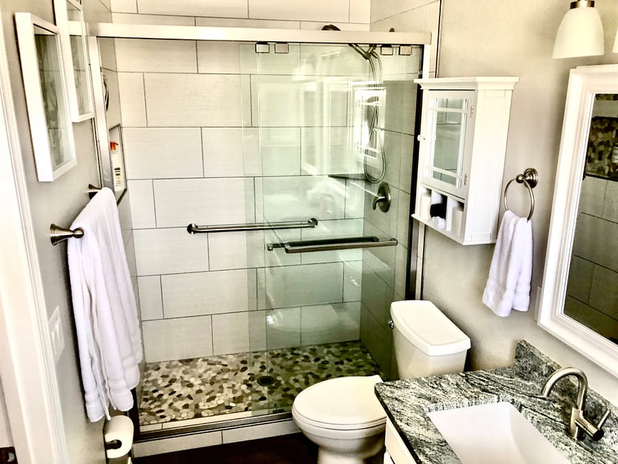 Primary bedroom bathroom walk in shower with river rock floor and safety grab rails. Towels, shampoo, conditioner and body wash provided