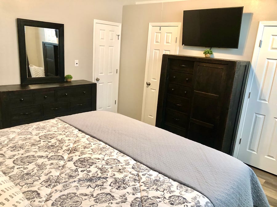 Primary bedroom with king bed, nightstands, chest, dresser, smart tv, dual closets and attached private bathroom