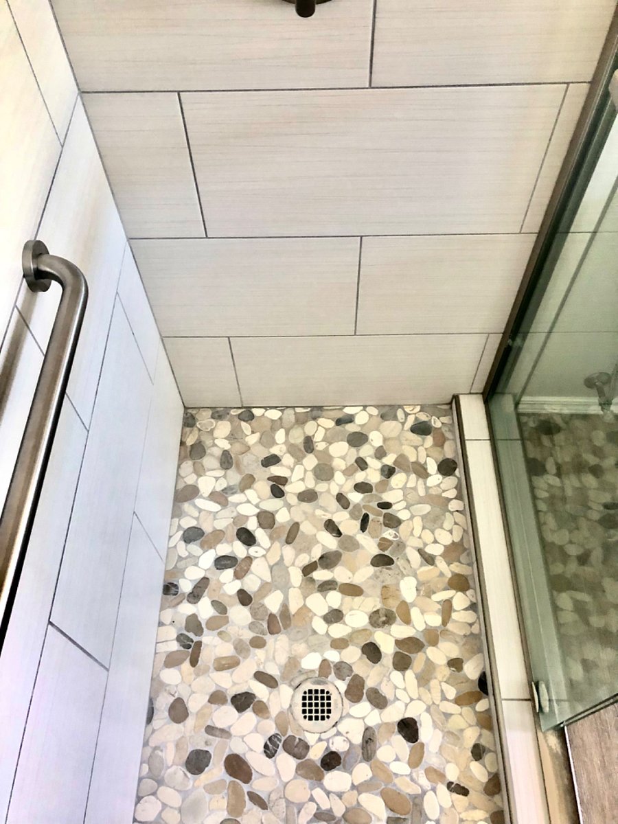 Primary bedroom bathroom shower with river rock floor and safety grab bars. Towels, shampoo, conditioner and body wash provided