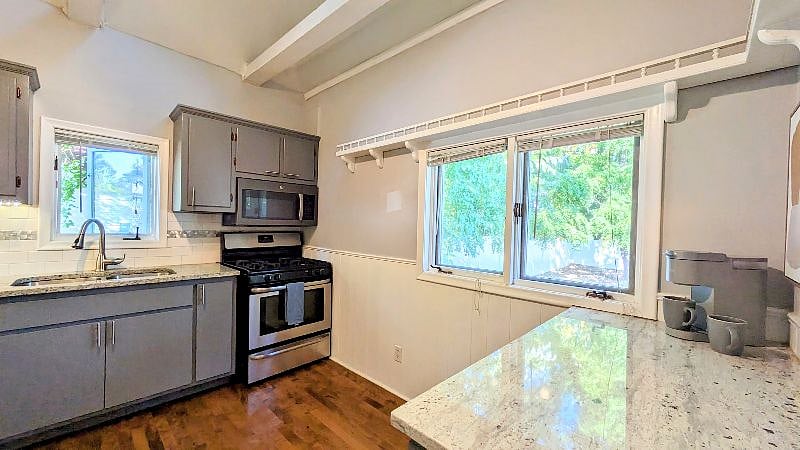 Gorgeous countetops and a spotlessly clean kitchen with Great backyard views (fully fenced yard!). Vaulted ceilings with beams!