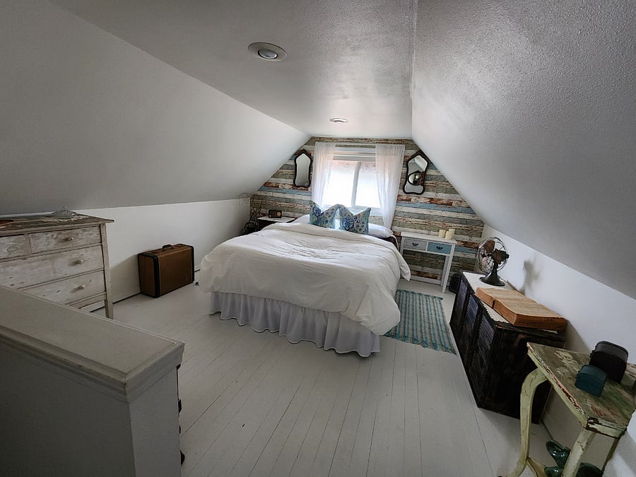 Upstairs master suite contains a hotel quality Queen size bed. This cozy1940's room is a step back in time with its original plank flooring.