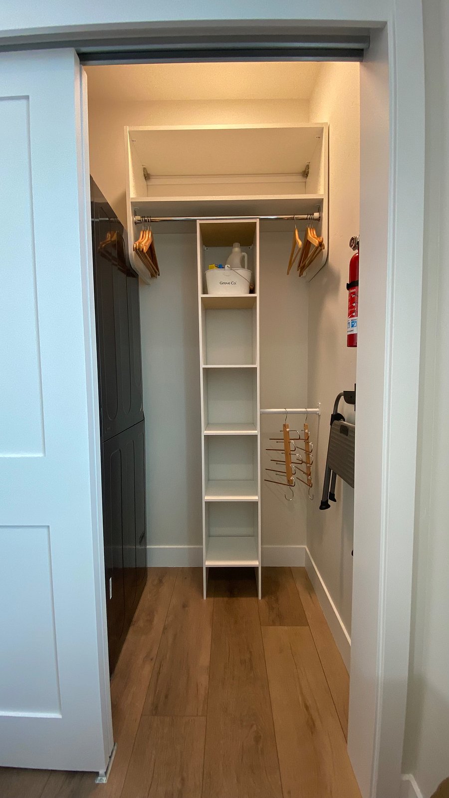 Bedroom closet with extra clothes rods, storage, step stool and fire extinguisher.