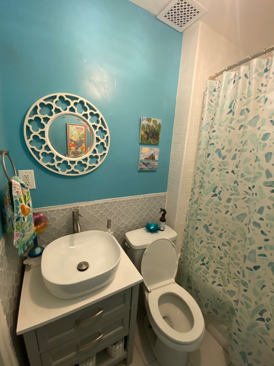 Blue bath with handheld bidet sprayer.