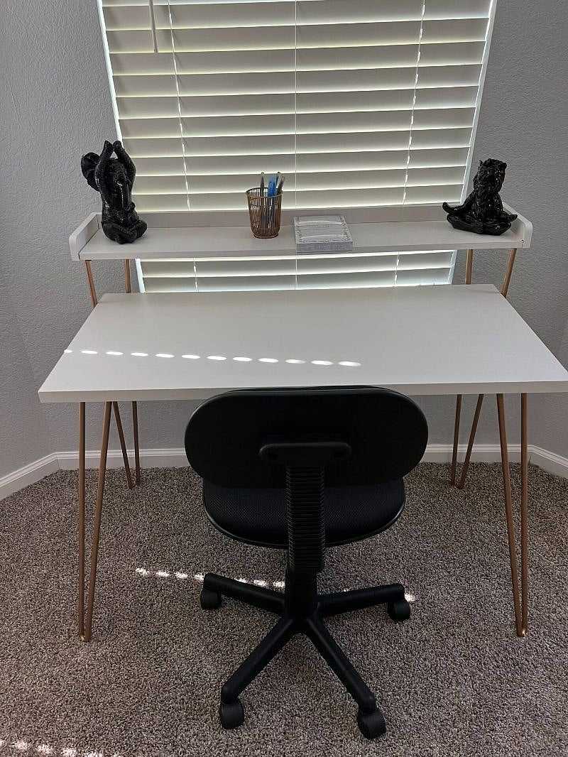 Desk in bedroom with pens and a notepad to jot anything down. Ther is an outlet behind the desk.
