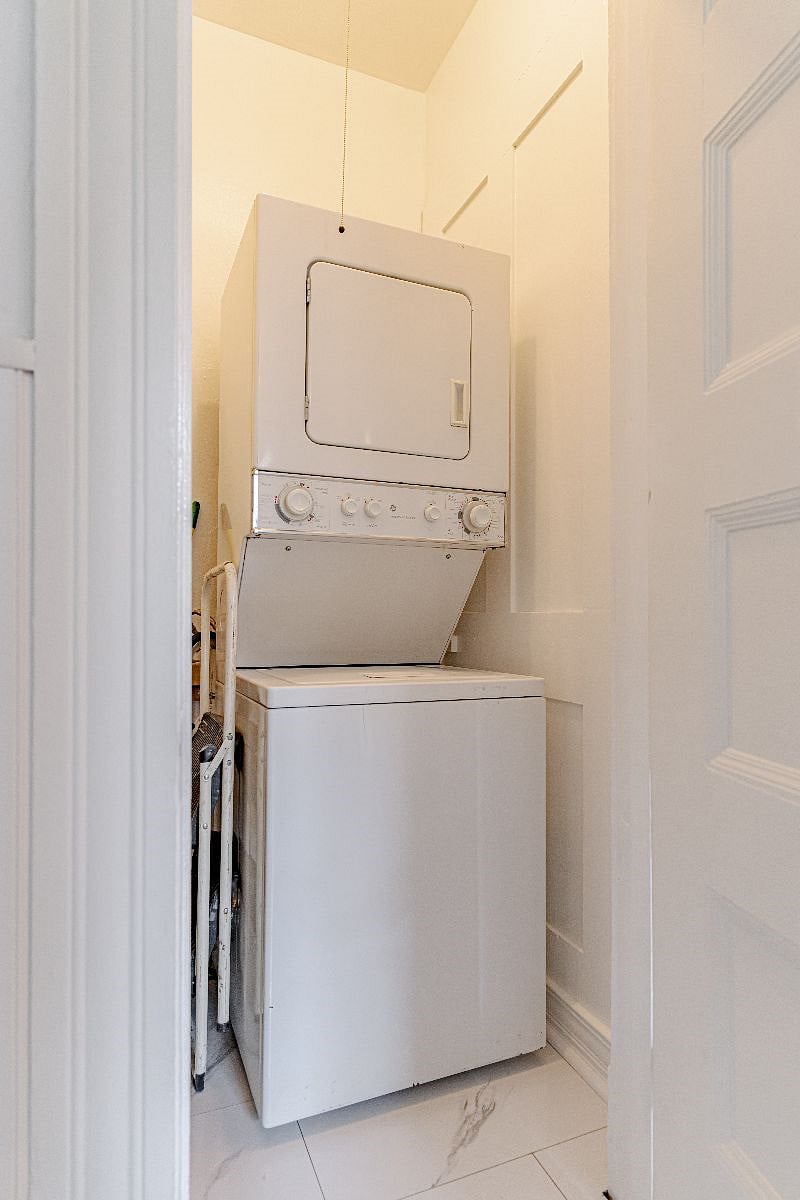 Kitchen pantry closet contains a stackable washer and dryer and shelving to the left of stackable is for storage.