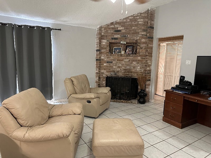 View of living room with fireplace and sun blocking curtains and leather furniture.