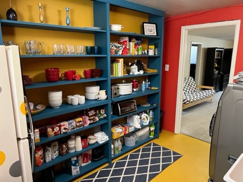 The kitchenette shelves. Plenty stocked with bowls, plates, cutlery, coffee, sugars, creams, toaster oven, slow cooker, and all sorts of cleaning materials.