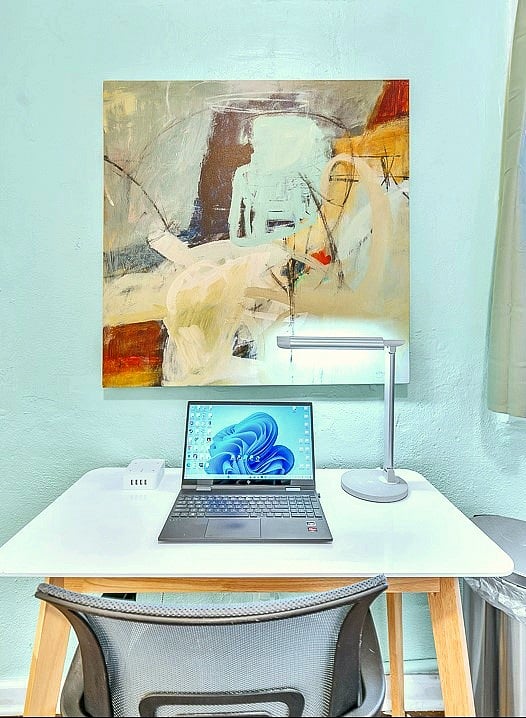 Desk space with adjustable lighting, power outlets for all your devices, and modern art.