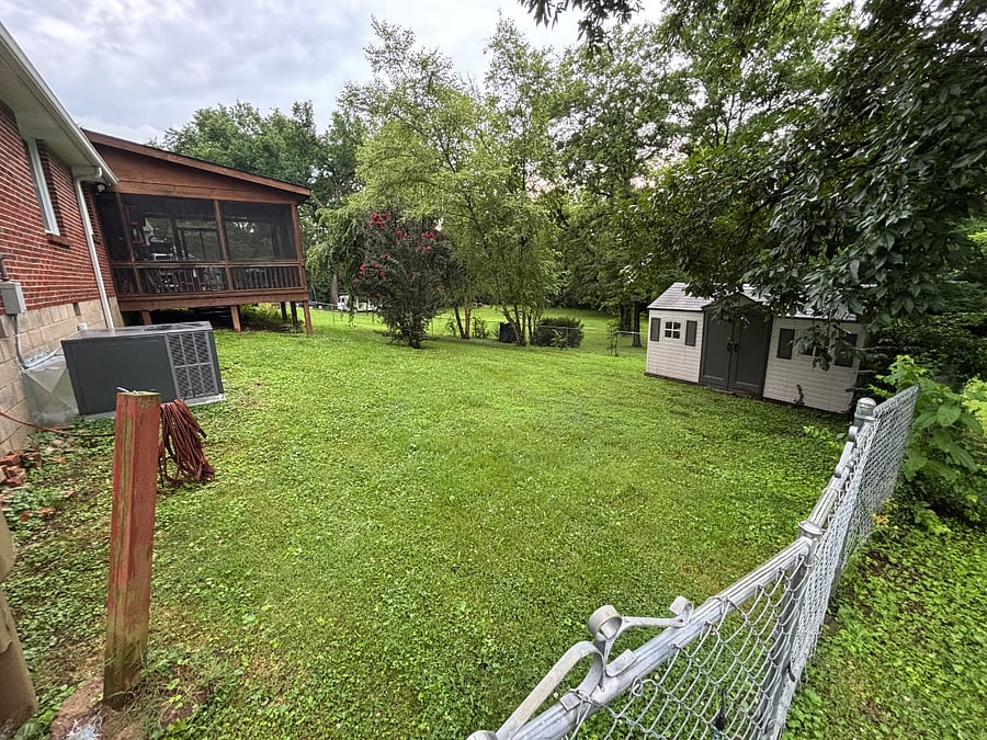 Backyard fenced in area and large lot beyond the fence.