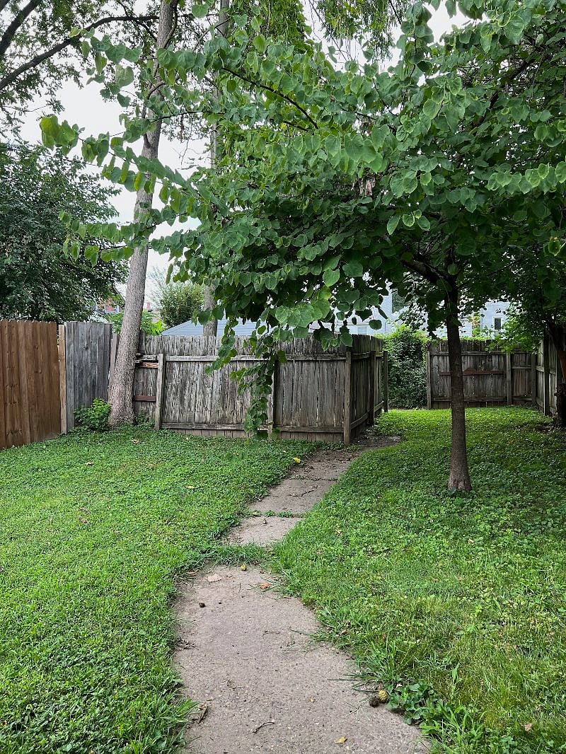 Lush green backyard with private driveway behind fence