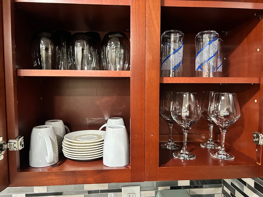 Fully stocked with glasses, bowls, and dishes.