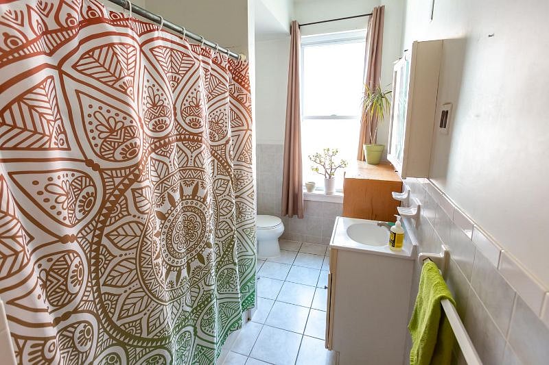 Typical bathroom with bath tub and detachable shower head. The frosted glass window is great for plants. We have a counter height storage cabinet.