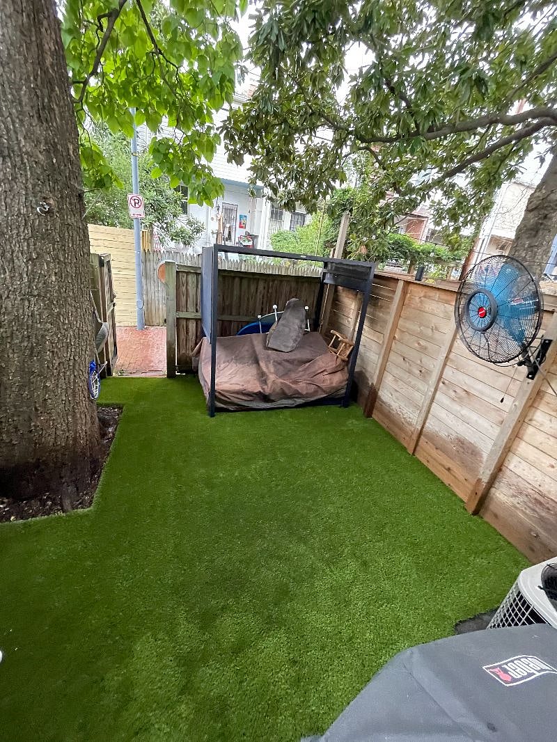 Fenced in outdoor space with turf, outdoor fan, & outdoor furniture.