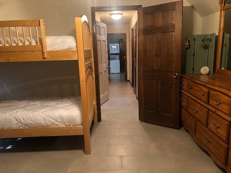 Tiled floor, bed and mirrored dresser.