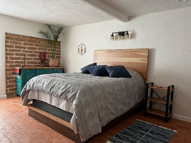 Master bedroom with queen size bed, brick floors and adobe accent wall