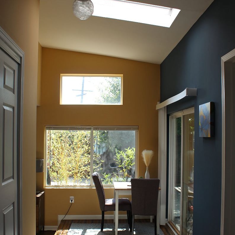 light-filled dining table with lots of windows, sliding door, and skylight