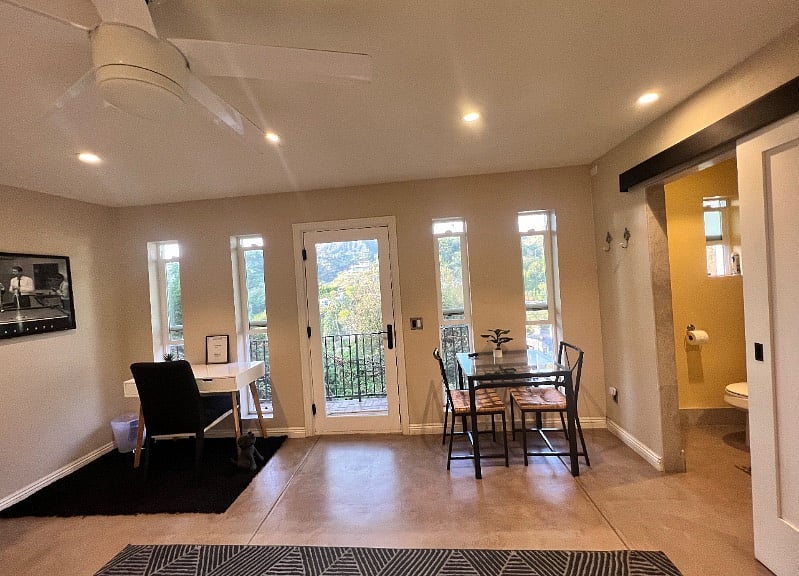View from bed. Left is a small desk and right a glass dining table with two chairs.