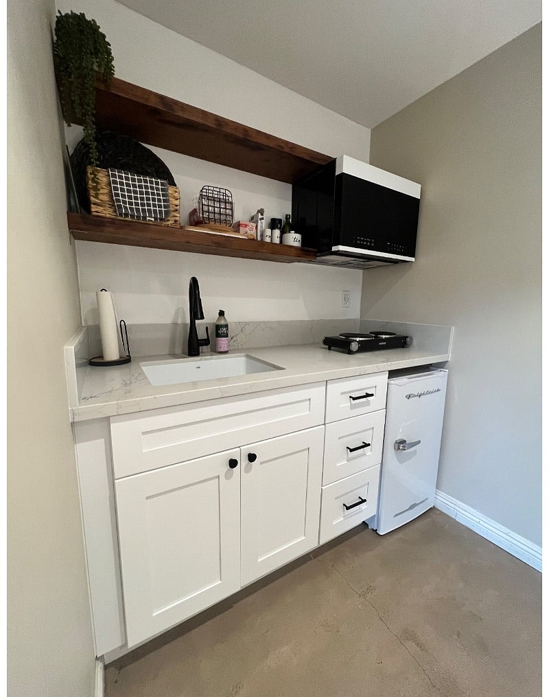 Kitchenette with microwave, double hot plates, fridge, coffee maker, tea kettle, toaster and cooking essentials, plus dishes.