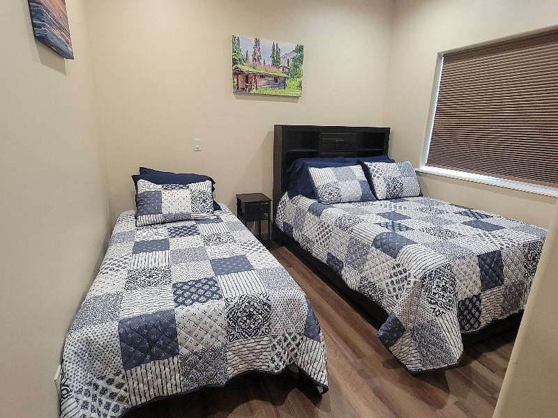 Bedroom 2 with full and twin size beds and darkening shade.  There are drawers at the foot of the full size bed.  There are also shelves and drawers in the headboard of the full size bed.