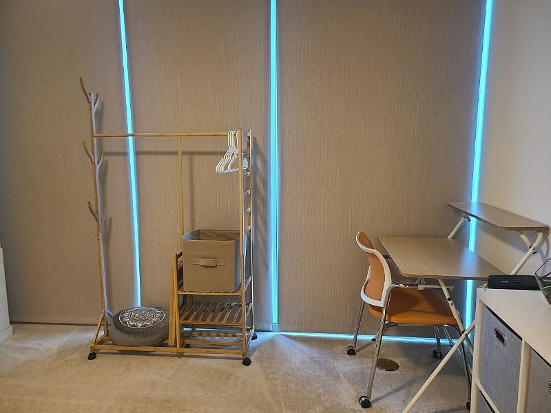 There is a clothing rack for extra storage and a desk/chair.