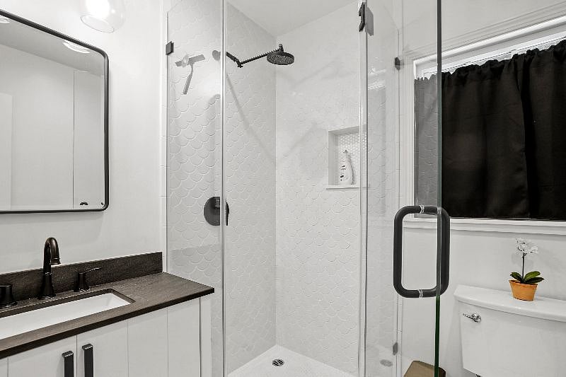 The shower is custom built with unique tile and quartz trim that matches the kitchen counters.