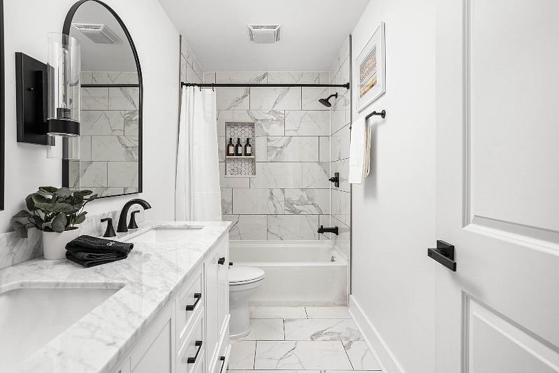 Step into the beautiful bathroom equipped with a shower, double sink vanity, and mirror.