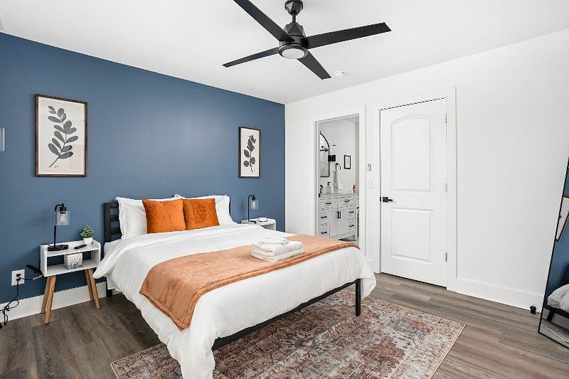 Experience the comfort of a queen-sized cozy bed complemented by a mirror, bedside table with a lamp, and
an attached bathroom.