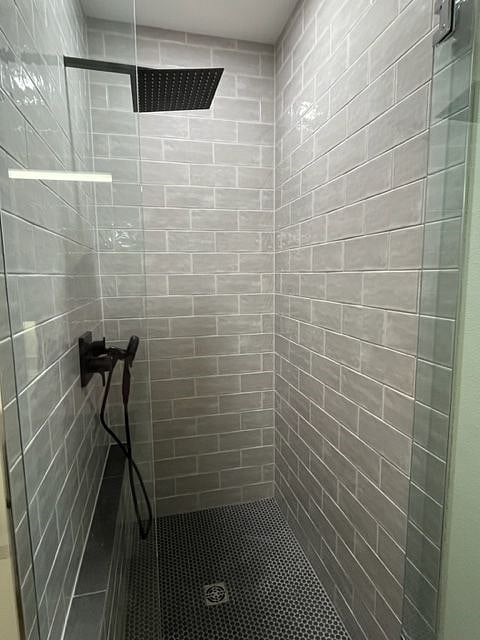 Tiled shower features large rain shower head, plus additional hand-held option. A built-in full-wall shelf provides space to hold shampoos and more.