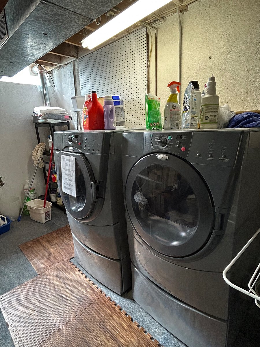 Large washer and dryer, utility sink, ironing board, and folding table in the basement.