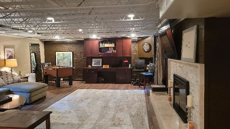 Large Living area with couches, chairs, large TV and fireplace with electric heater in it.