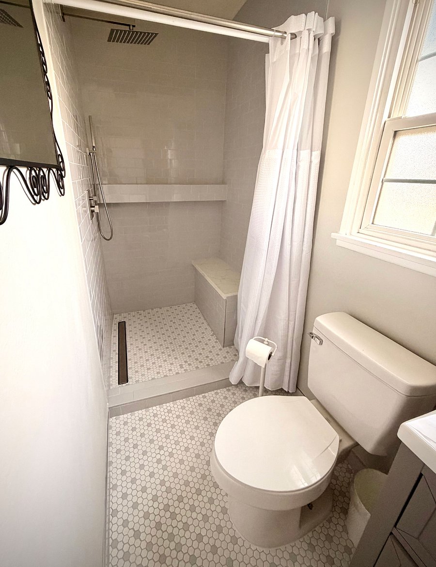 Enjoy a fully remodeled private bathroom featuring sleek subway tile from floor to ceiling, a modern rainfall shower with handheld option, and elegant custom granite finishes. The built-in bench and spacious 4-foot shelf add both comfort and convenience, creating a clean, spa-like experience.
