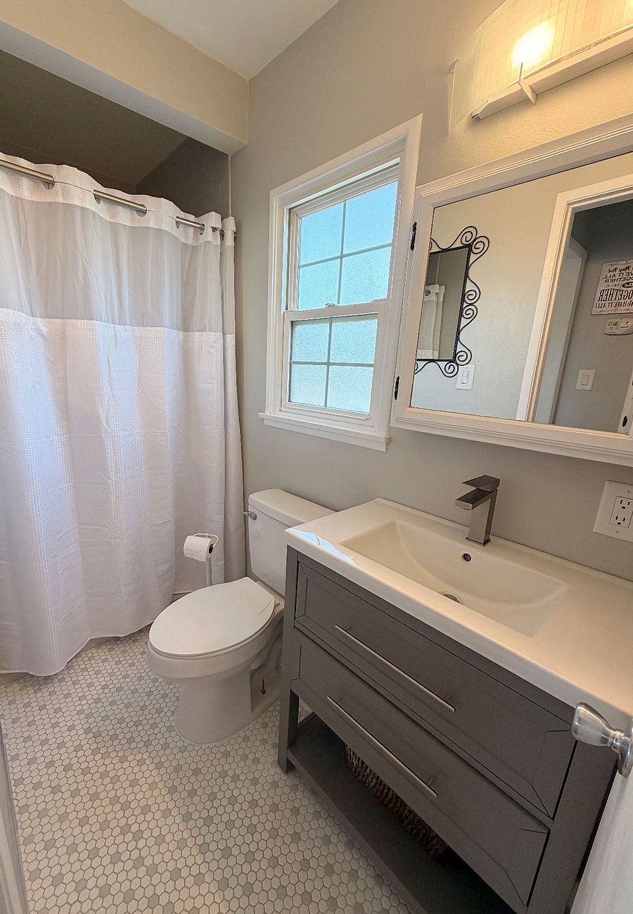 Step into a beautifully upgraded private bath with brand-new tile flooring, fresh paint, and all-new plumbing. The oversized rainfall shower, handheld sprayer, and custom granite bench and shelf make this space both luxurious and functional.