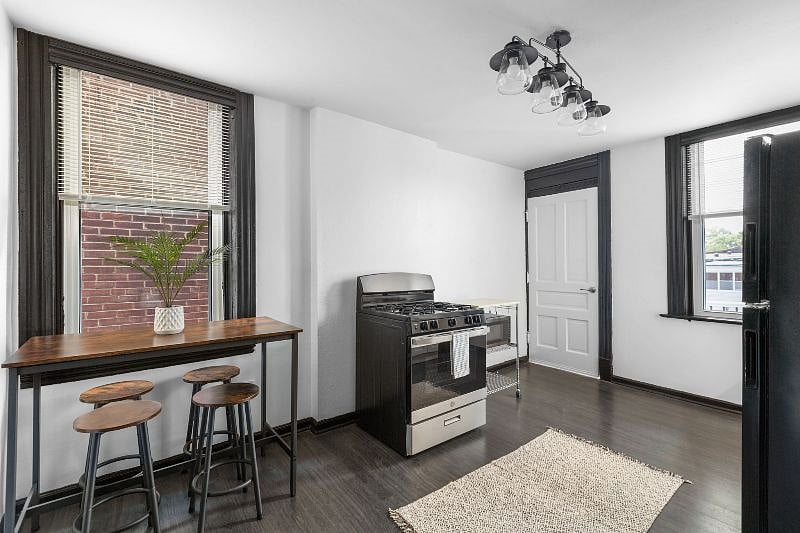 Kitchen - View from entrance of bar height table with 4 stools, stove, microwave cart, and back door to balcony.