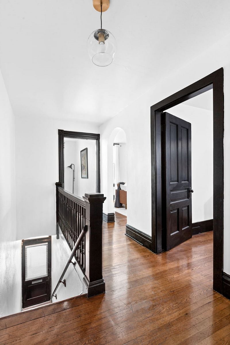 Hallway - view of railing for front staircase, study entrance (left), king bedroom door (right) and arched entryway to living room (middle).