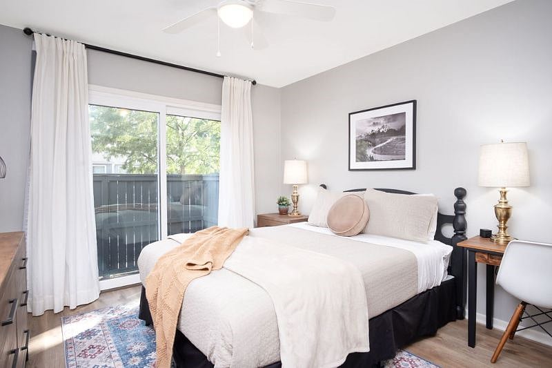 Front bedroom with patio door and blackout curtains, queen bed, large dresser, nightstand, desk, smart tv, large closet.