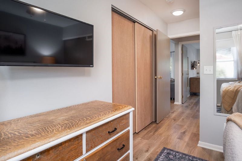 Rear bedroom hallway with triple closet access to washer and dryer, furnace & water heater, and storage shelves.