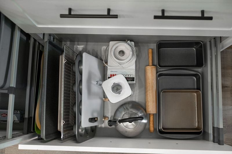 Kitchen drawer with cookie sheets, muffin tins, bread & cake pans, cooling rack, cutting board, rolling pin, blender, casserole dish, water kettle.