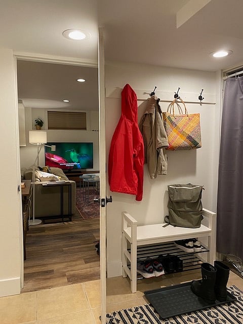 As you walk in , on the left is an area with 4 hooks, shoe rack and seat and a place to put shoes on rubber mat. On the left you will see a door which is one of the entry points to studio with place to drop your keys on console table, sofa and TV in view.