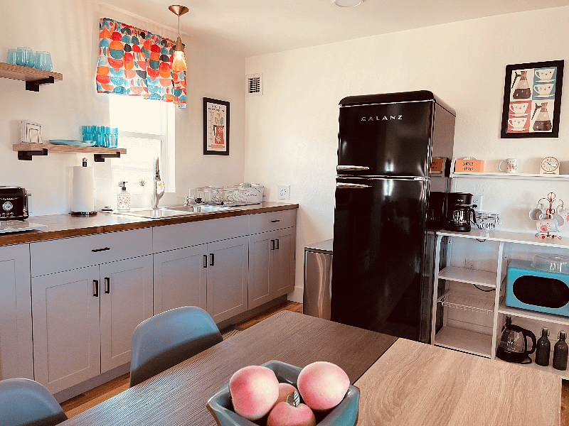 Kitchen with fridge, gas range and oven, microwave, toaster, coffee pot and hot water kettle