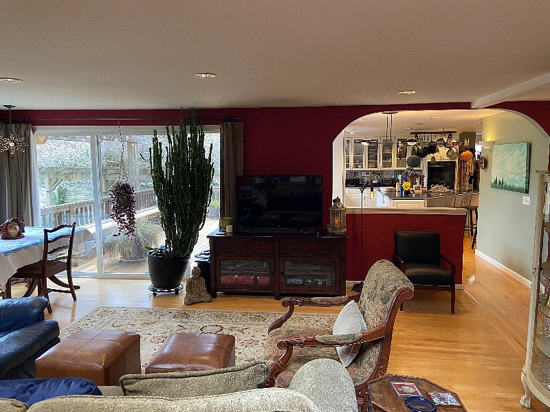 Den view from behind the couch and into the kitchen, den and deck. Notice floor to ceiling glass windows and doors. Sky lights also add to the natural light filled room.