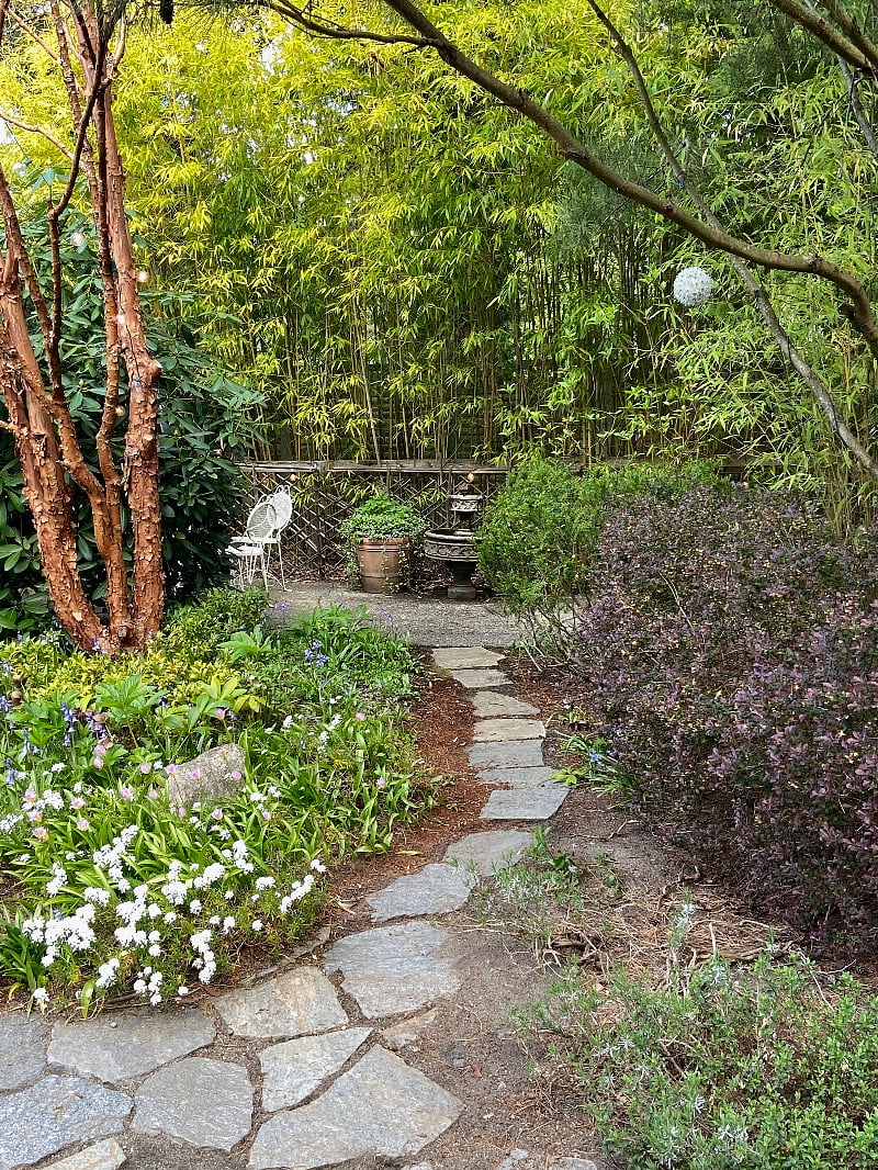 Front yard's secluded garden with a fountain and seating.