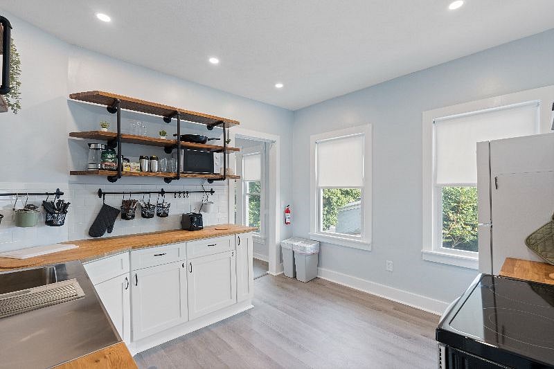 It boasts modern appliances such as a dishwasher, garbage disposal, electric range, refrigerator, microwave, coffee maker, toaster, and electric kettle.