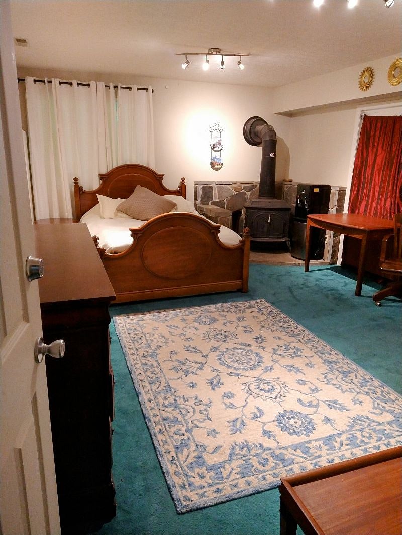 Unit 3:  Second one-bedroom unit with kitchenette.  Bedroom with queen bed, attached full bathroom (ground level walk-out). Wood stove pictured is not functional.