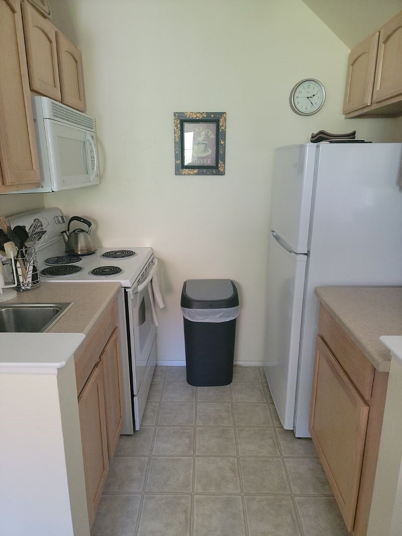 Kitchen includes full-size electric range/oven, microwave, apartment-size refrigerator/freezer and disposal.