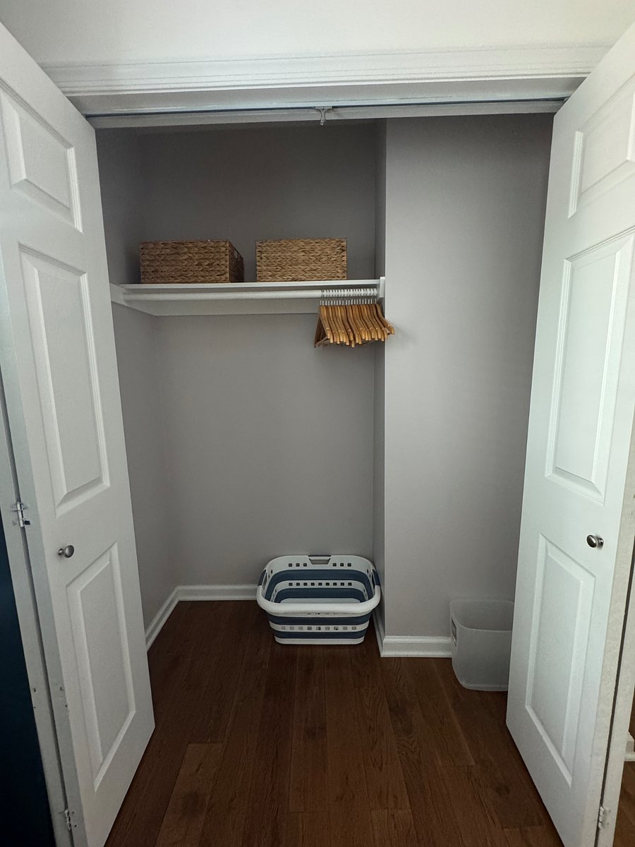 Spacious bedroom closet with wooden hangers, laundry basket, and storage baskets.