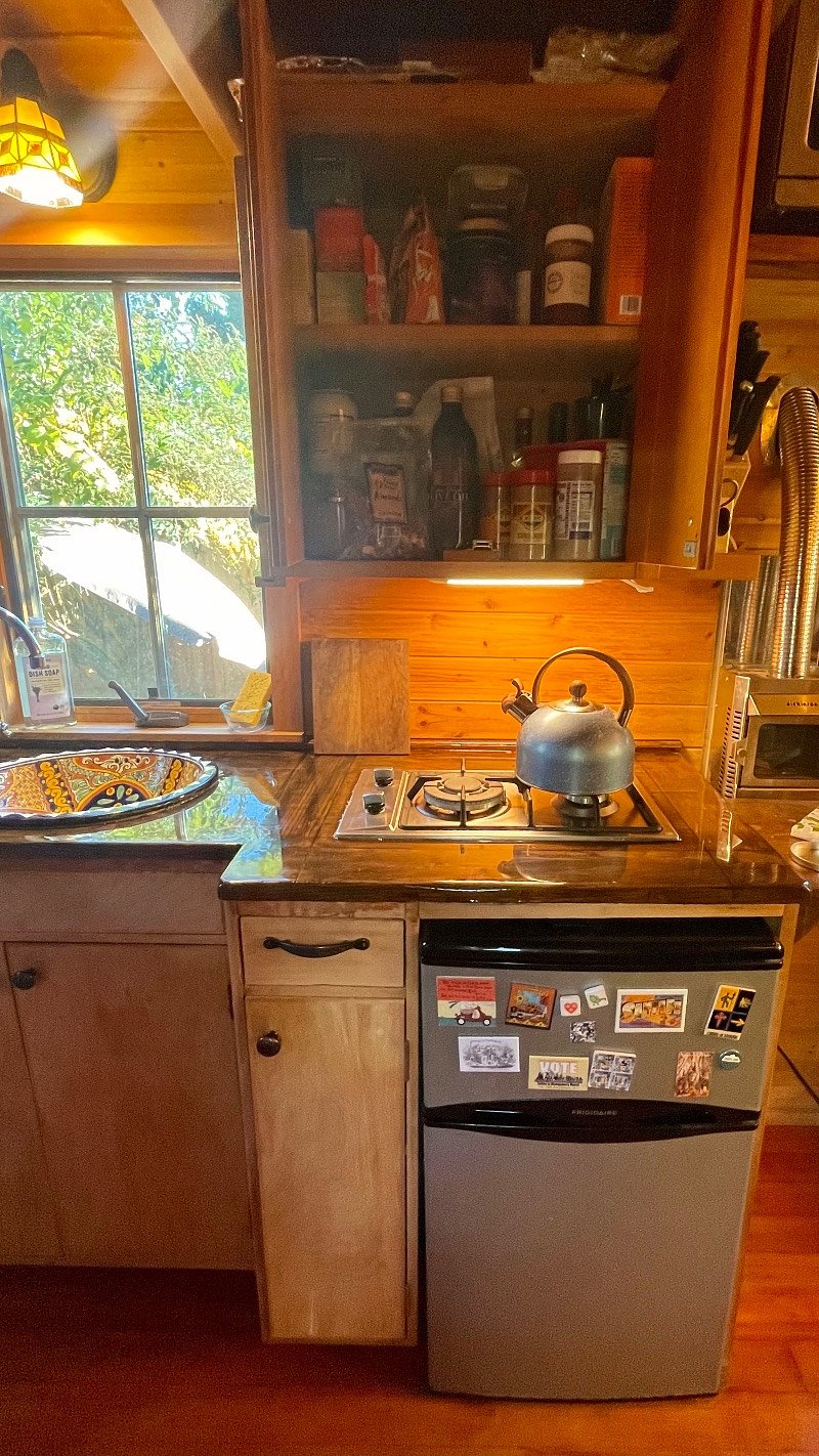 The kitchen - mini fridge with separate freezer section, two burner stovetop, sink, and pantry